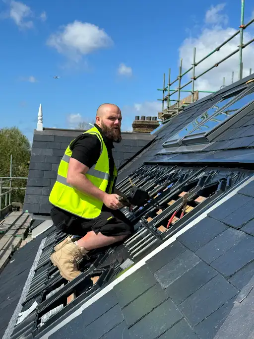 A man in a safety vest working on a roof.
